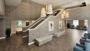 Un hall d’entrée spacieux, doté d’un escalier moderne, de coins salon et d’œuvres d’art accrochées aux murs.