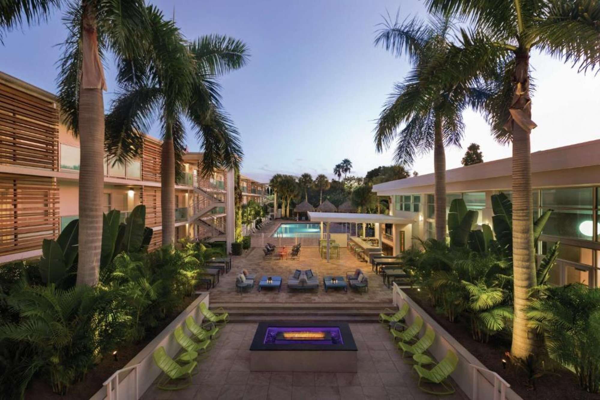A resort with a pool, lounge chairs, and palm trees.