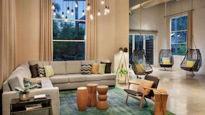 Een moderne woonkamer met een bank, bijzettafels, hangstoelen en grote ramen.