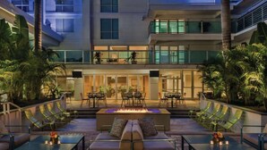 A modern outdoor lounge area with a fire feature, seating, and a view of the building's interior. - Luxury Retreat In Tampa | Free Airport Shuttle (Tampa)