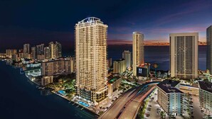 A high-rise hotel with multiple floors, a rooftop pool, and a view of the city skyline at dusk. - Direct Ocean Views + Rooftop Pool. Bar. Tennis. (Hollywood)