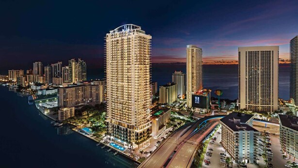 A high-rise hotel with multiple floors, a rooftop pool, and a view of the city skyline at dusk. - Steps from Hollywood Beach + Rooftop Pool. Bar. (Hollywood)