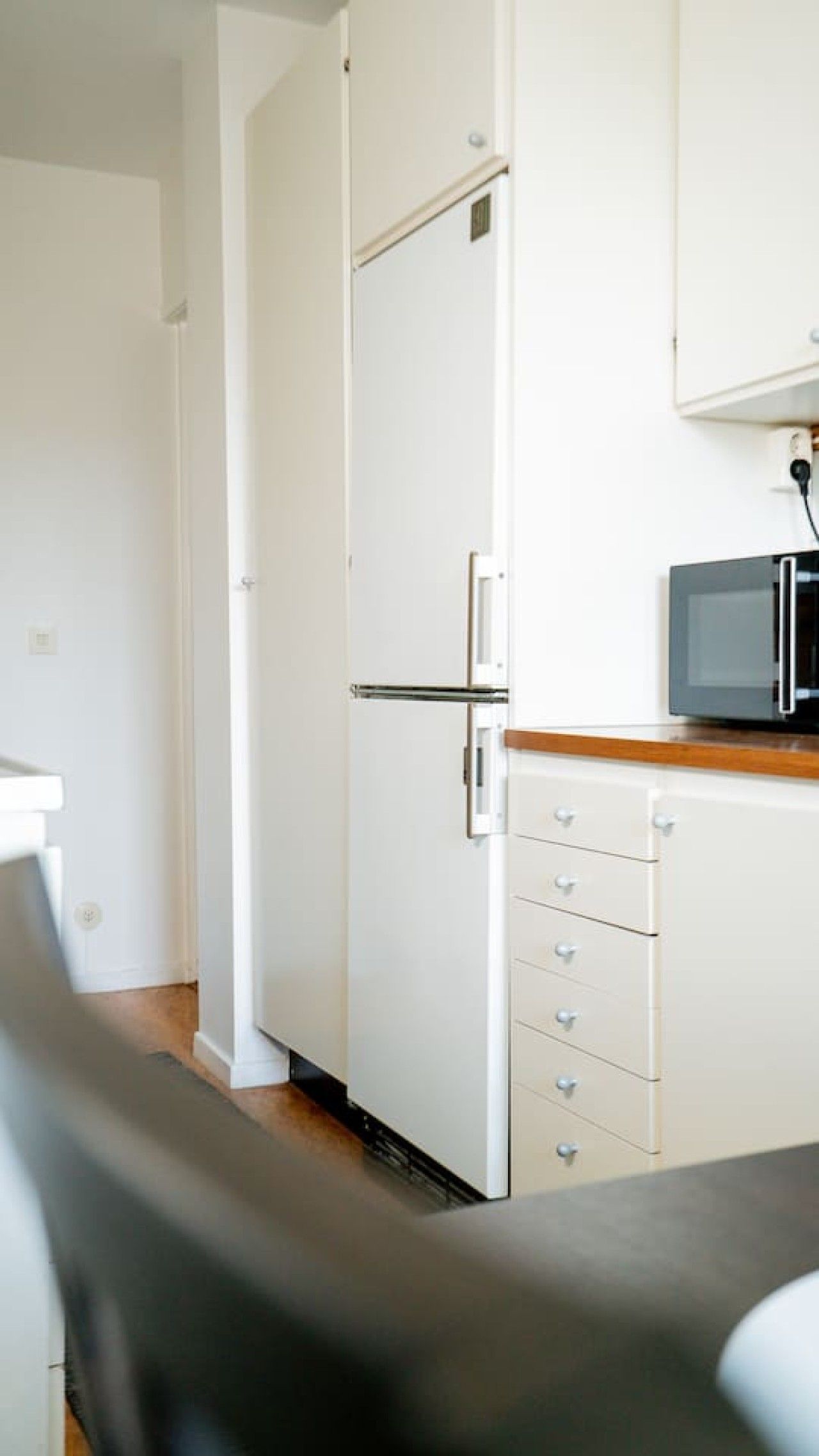 Eine kleine Küche mit einer Mikrowelle, einem Kühlschrank und einer Holz Arbeitsplatte.