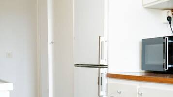 Eine kleine Küche mit einer Mikrowelle, einem Kühlschrank und einer Holz Arbeitsplatte.