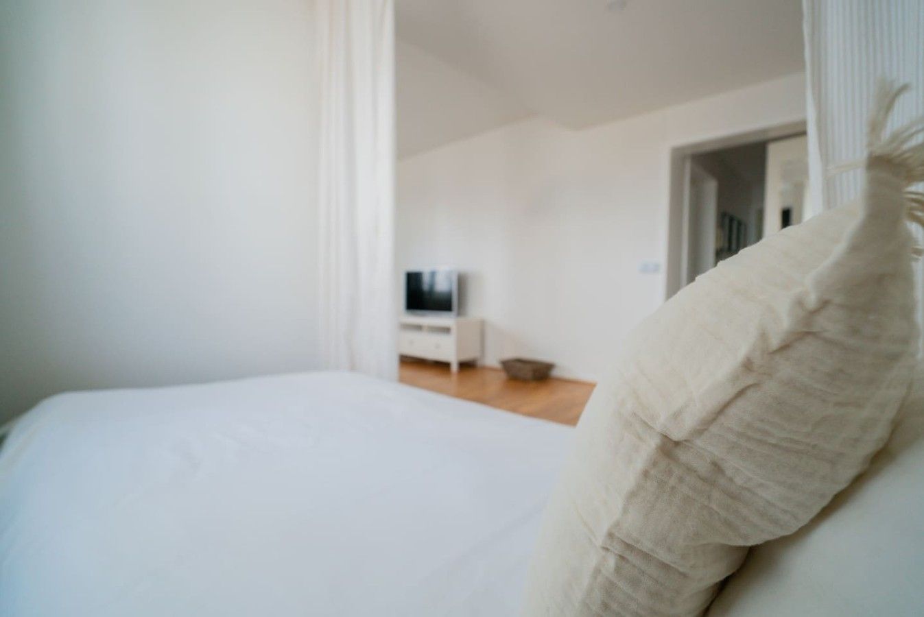 A bedroom with a bed, a television, and a white dresser.