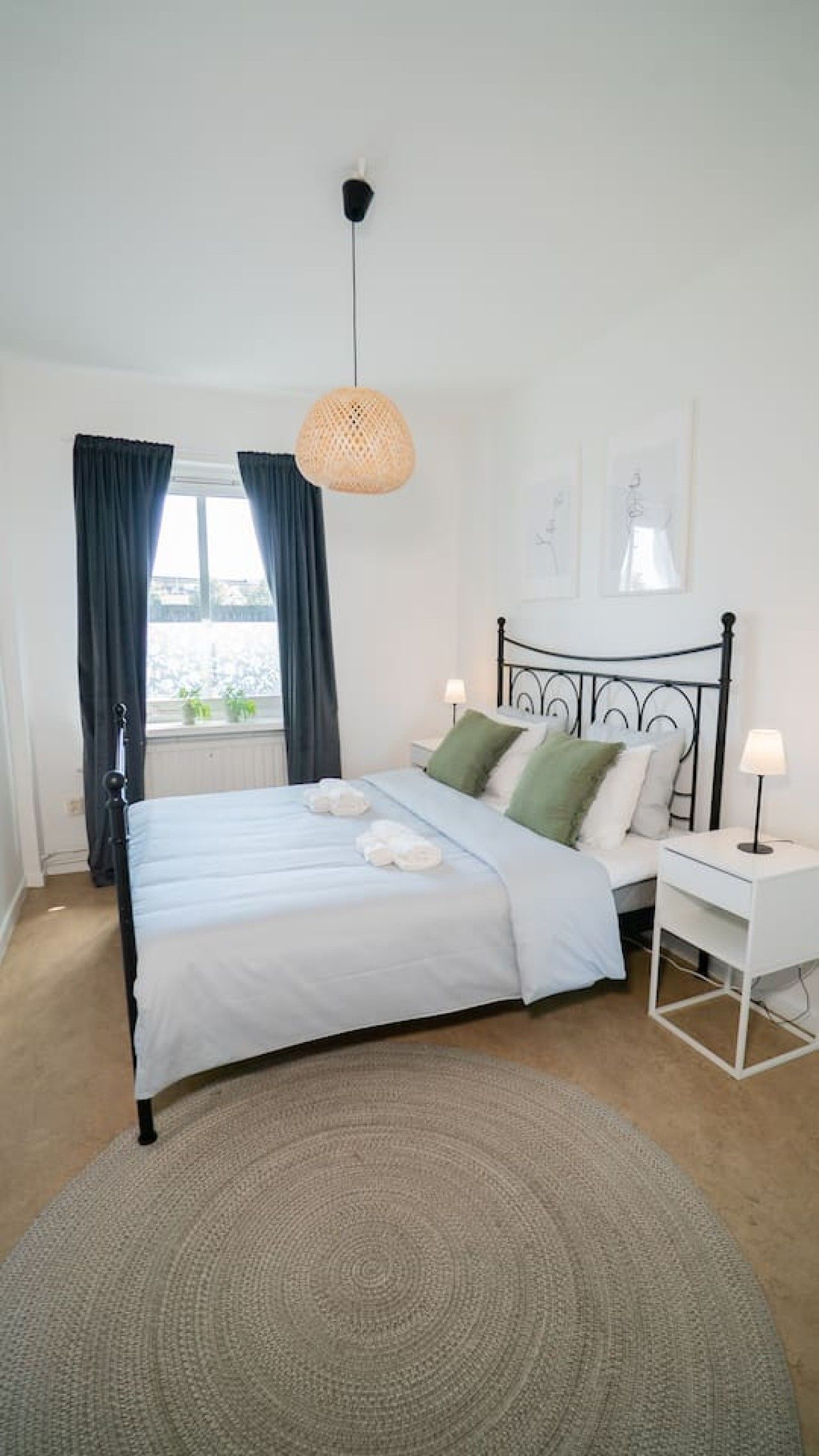 Une chambre à coucher avec un lit, des tables de chevet, un luminaire suspendu et une vue sur l’extérieur.