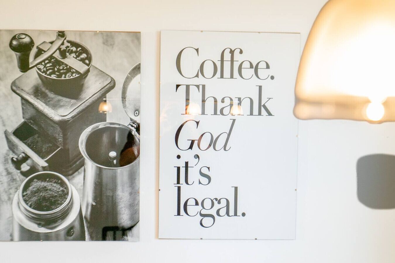 En væg med en vintage kaffekværn og et skilt med teksten 'Coffee. Thank God it's legal.'