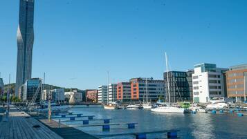 A marina with boats docked, a tall building, and a variety of other buildings in the background.
