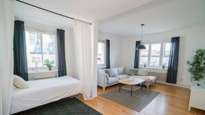 Ett modernt hotellrum med en säng, en soffa, ett soffbord och utsikt över staden.