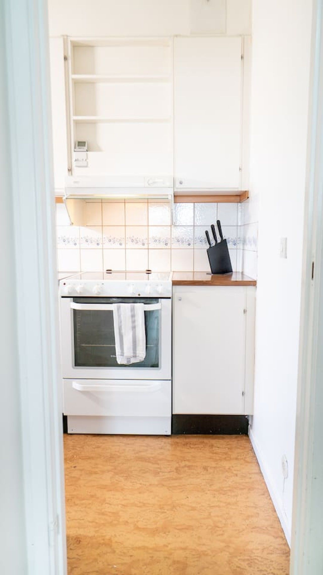 A kitchen with white cabinets, a stove, and a black knife block.