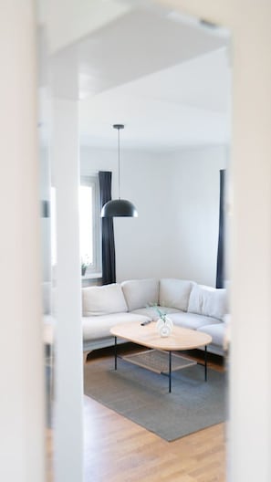 Ett modernt vardagsrum med en soffa, ett soffbord och en hängande taklampa.