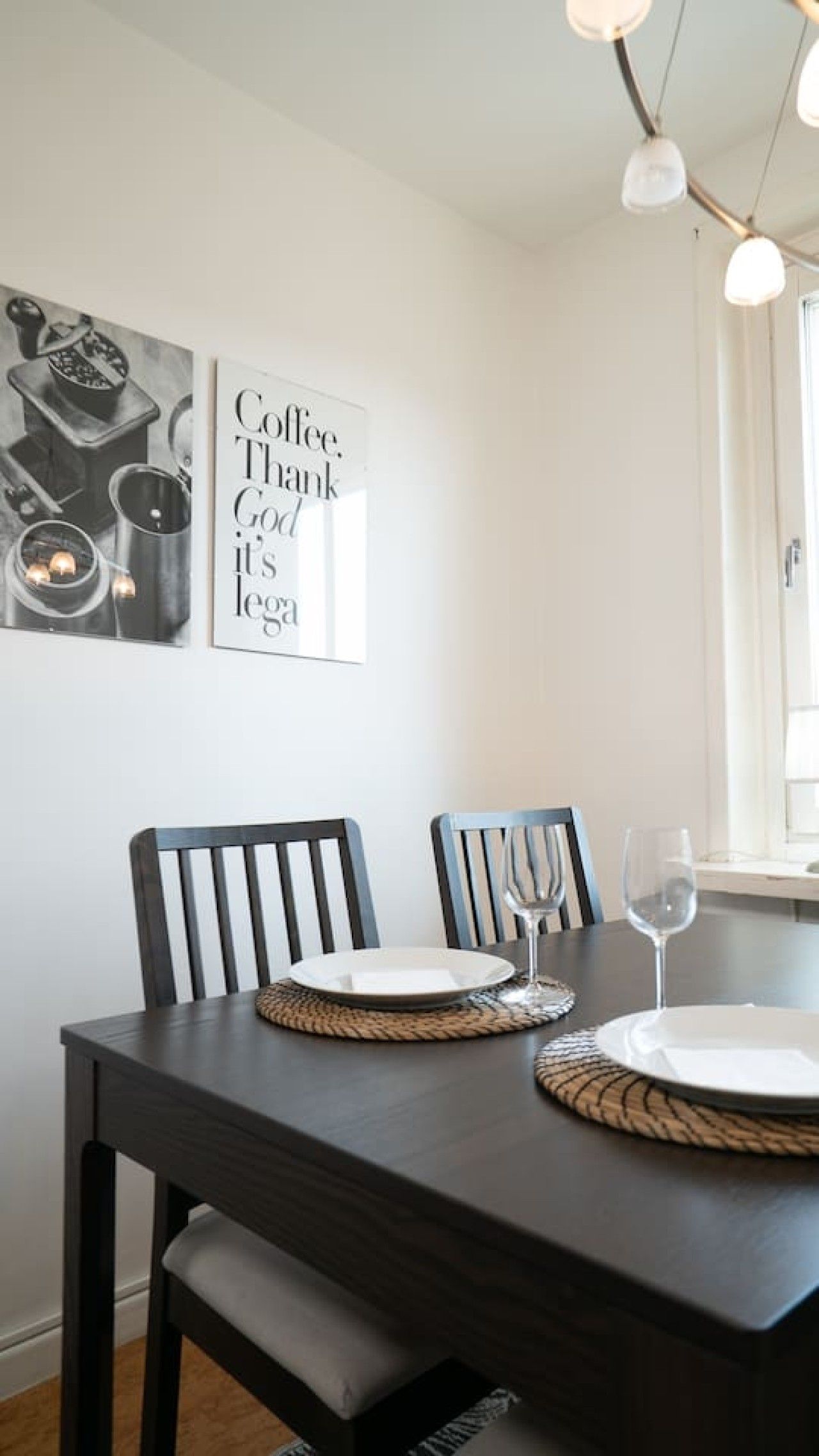 A dining table with two chairs, a glass, and a plate.