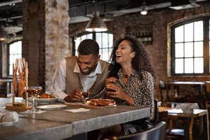 A couple dining at a restaurant with exposed brick walls and large windows. - Rooftop Fitness in Midtown Atlanta | Restaurants (Atlanta)