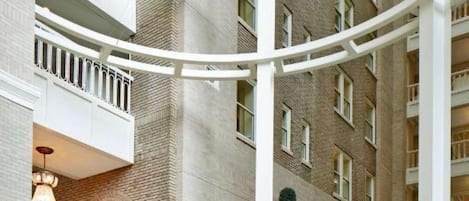 Een ruime lobby met een hoge plafond, een centraal gelegen zitgedeelte en een groot raam met uitzicht op de buitenkant van het gebouw.