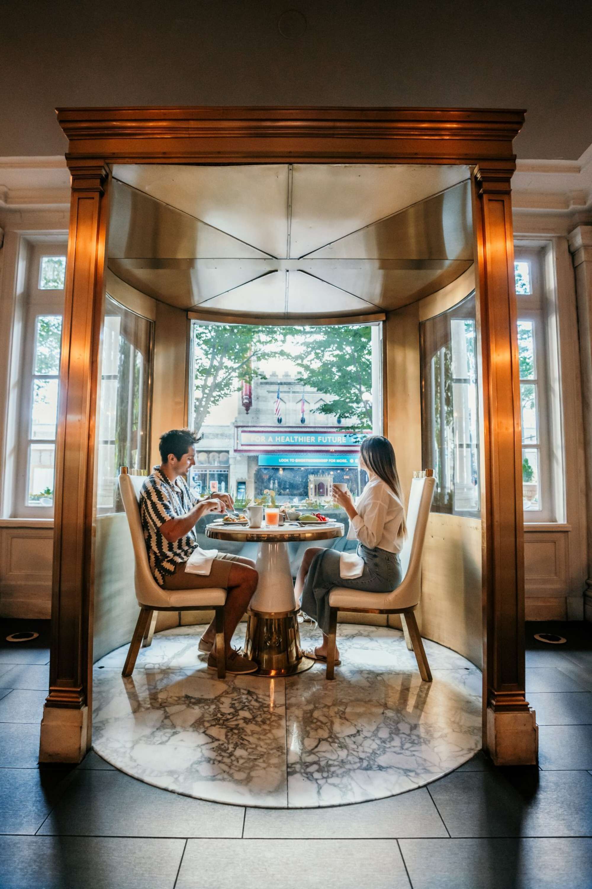 A couple dining at a table in a corner with a view of the street.