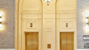 A lobby with a grand chandelier, two elevators, and a seating area with a patterned rug. - Fox Theatre Next Door | Rooftop Fitness + Dining (Atlanta)