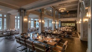 A spacious dining area with multiple tables, high ceilings, and large windows allowing natural light. - Fox Theatre Next Door | Rooftop Fitness + Dining (Atlanta)
