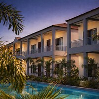 A multi-story hotel with balconies, a swimming pool, and tropical landscaping.