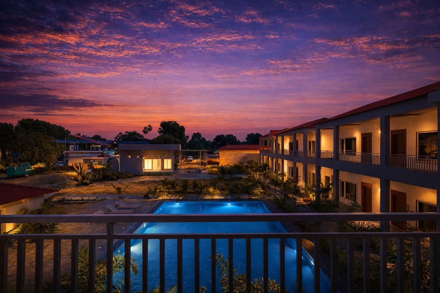 Un hotel con piscina, varios balcones y vistas al atardecer.