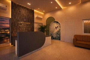 A reception area with a reception desk, air conditioning units, a wall-mounted artwork of birds, and a sofa.