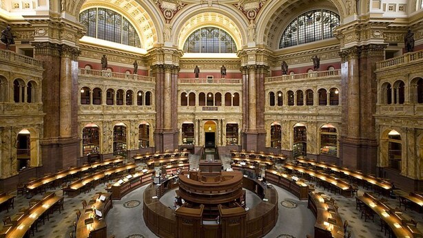 Una biblioteca imponente con varios niveles de lectura, arquitectura ornamentada y una zona central circular para leer.