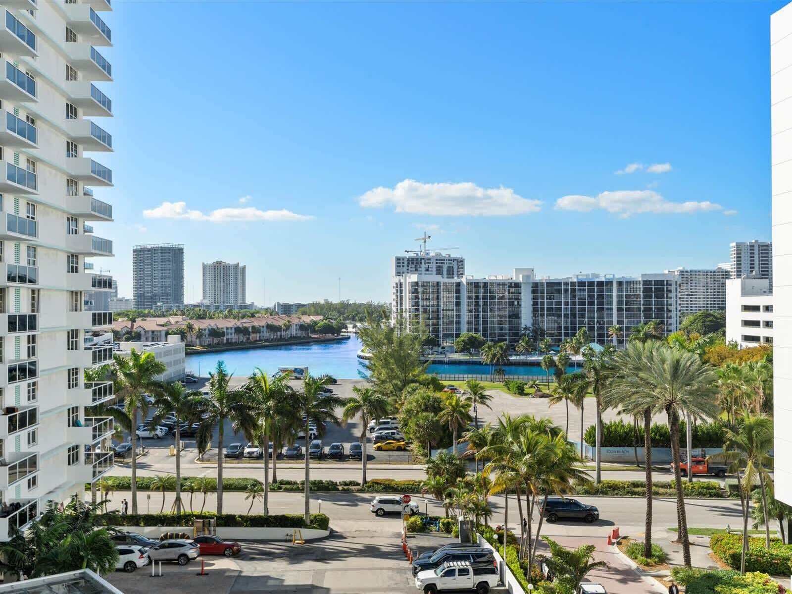 A high-rise hotel with a view of a marina and a large building in the background.
