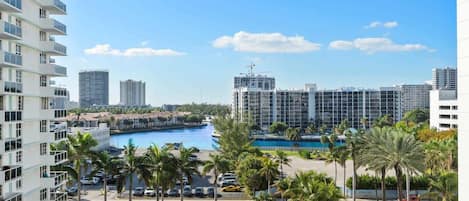 A high-rise hotel with a view of a marina and a large building in the background.
