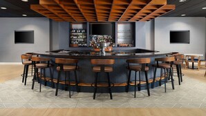 A bar area with a central island, multiple stools, and a wall-mounted TV. - Near Pimlico Race Course + Gym. Pickleball (Pikesville)