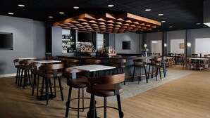 A modern bar area with wooden bar stools, a central bar counter, and a patterned rug on the floor. - Close to Maryland Zoo in Baltimore + Dining & Gym (Pikesville)
