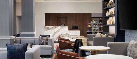 A modern hotel lobby with a seating area, a reception desk, and a television.