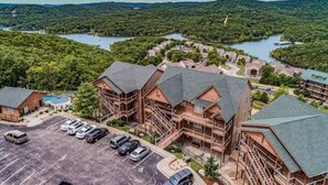 Un chalet comprenant plusieurs bâtiments, un parking et un lac en arrière-plan.