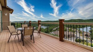 A wooden deck with a table and chairs, overlooking a river and hills. - L-8 Stunning views close to SDC (Branson)