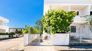 Un lotissement résidentiel fermé, avec un bâtiment blanc, un vélo et un arbre.