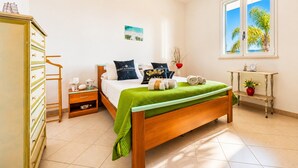 Une chambre à coucher comprenant un lit, une table de chevet, une commode, une fenêtre avec vue et une petite table placée près du lit.