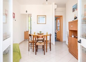 Ein Essbereich mit Holztisch und Stühlen, einem gerahmten Bild an der Wand und einer Holzkommode mit einem kleinen Schiffmodell.