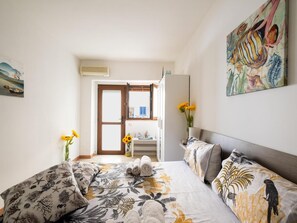 Ein Schlafzimmer mit Bett, Kissen, einem Nachttisch, einem Spiegel und einem Gemälde.