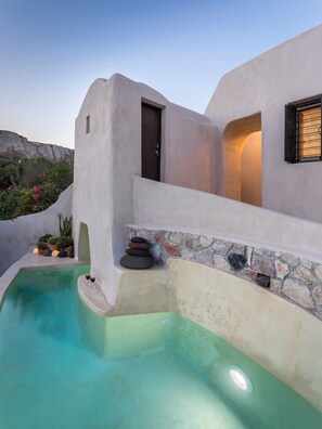 A modern building with a swimming pool, a door, and a window with a wooden frame. - Canava Villas Santorini (Santorini)