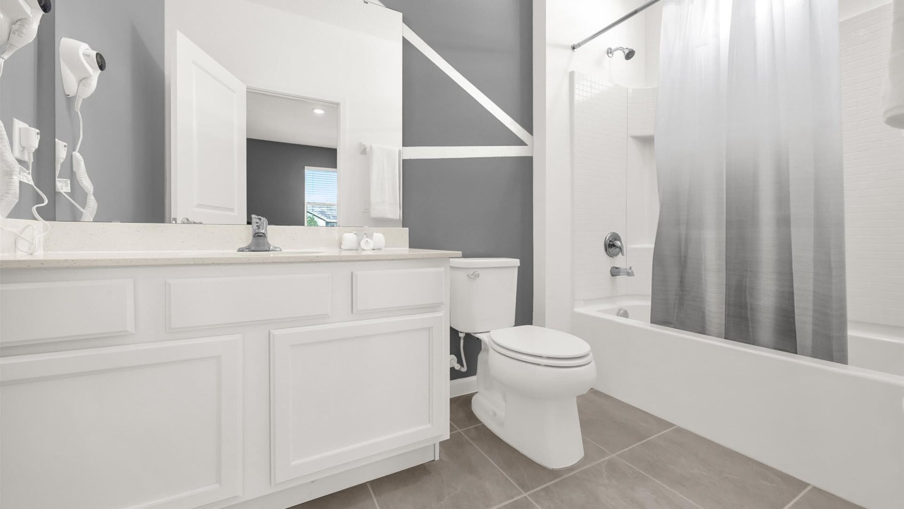 Un baño moderno con un tocador blanco, inodoro y zona de ducha.