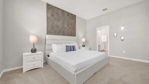 A modern bedroom with a large bed, two bedside tables with lamps, a large mirror, and a textured wall panel. - Upstay Spacious Villa w Pool Hot Tub Game Room (Kissimmee)