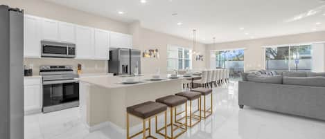 A modern kitchen with white cabinets, stainless steel appliances, and a central island with bar stools.