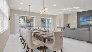 A dining area with a long table set for six, surrounded by six chairs. - Upstay Spacious Villa w Pool Hot Tub Game Room (Kissimmee)