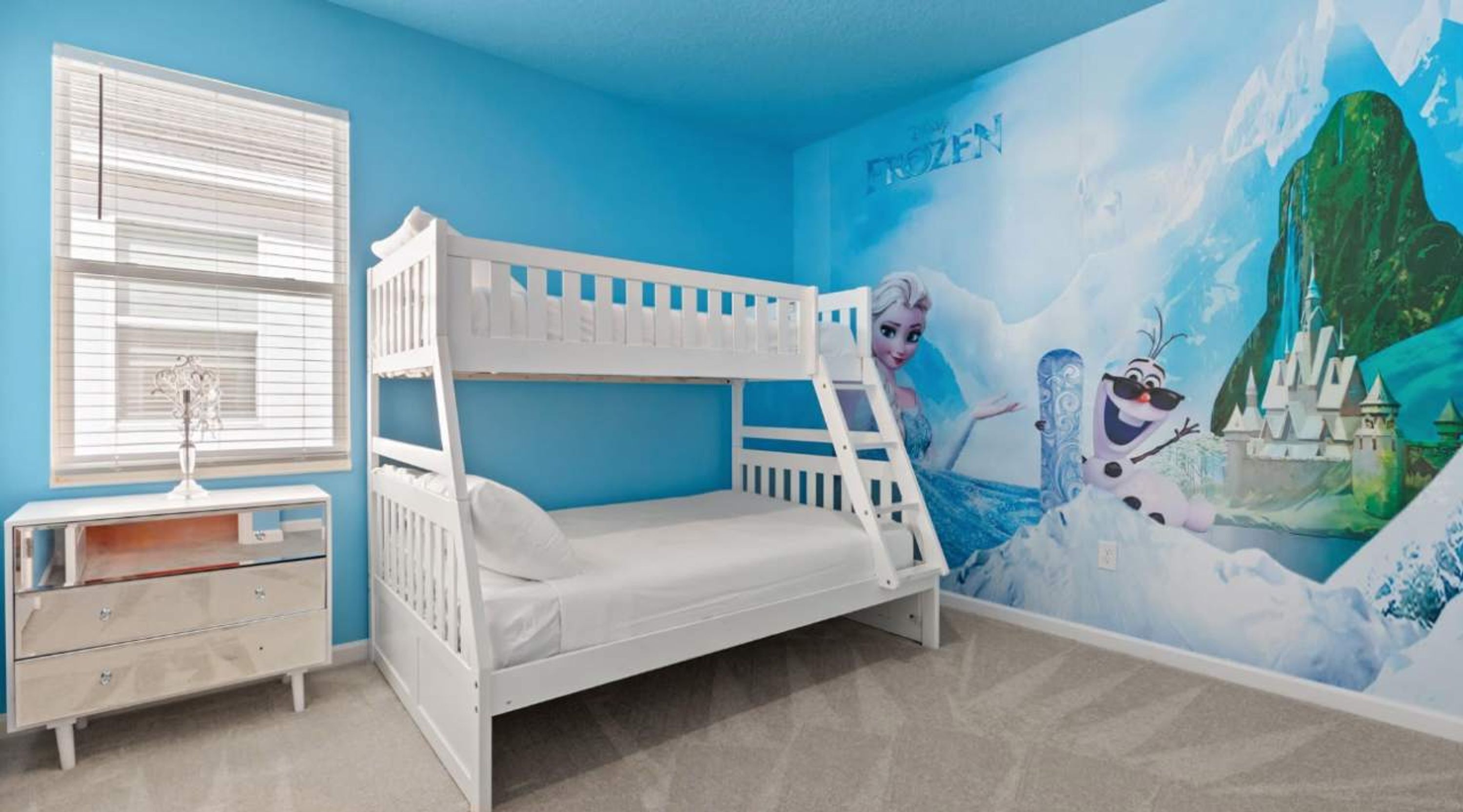 A child's bedroom with a bunk bed, a dresser, and a mural of Frozen characters.