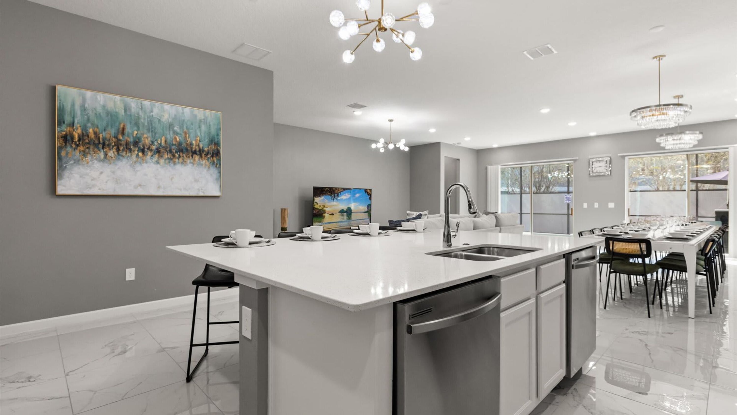 A modern kitchen with a large island, a dining area, and a view of the outdoors.