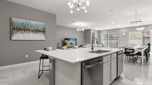 A modern kitchen with a large island, a dining area, and a view of the outdoors. - Upstay Veranda Palms Villa Pool Hot Tub Games (Kissimmee)