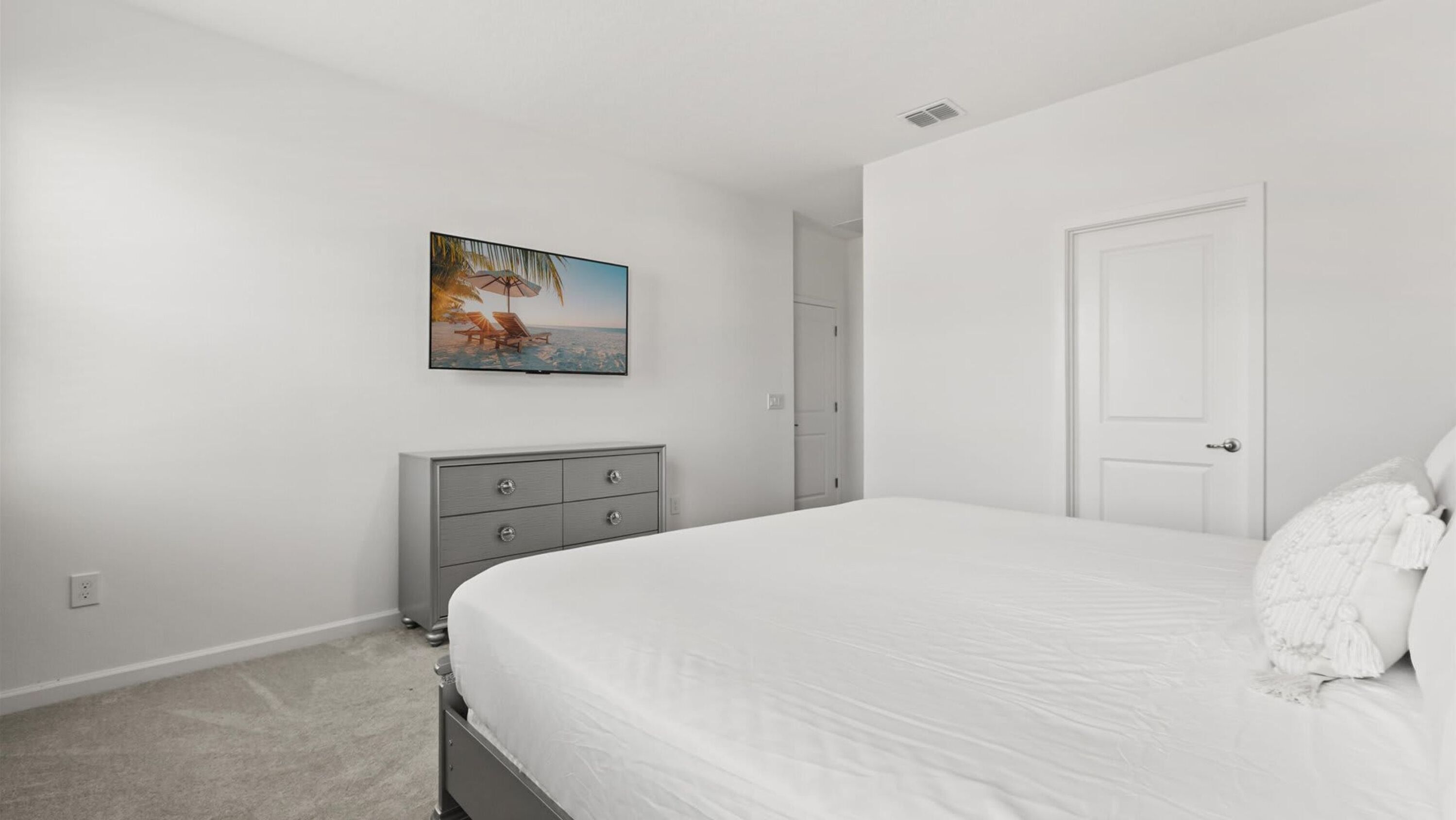 A bedroom with a bed, a dresser, a door, and a painting on the wall.