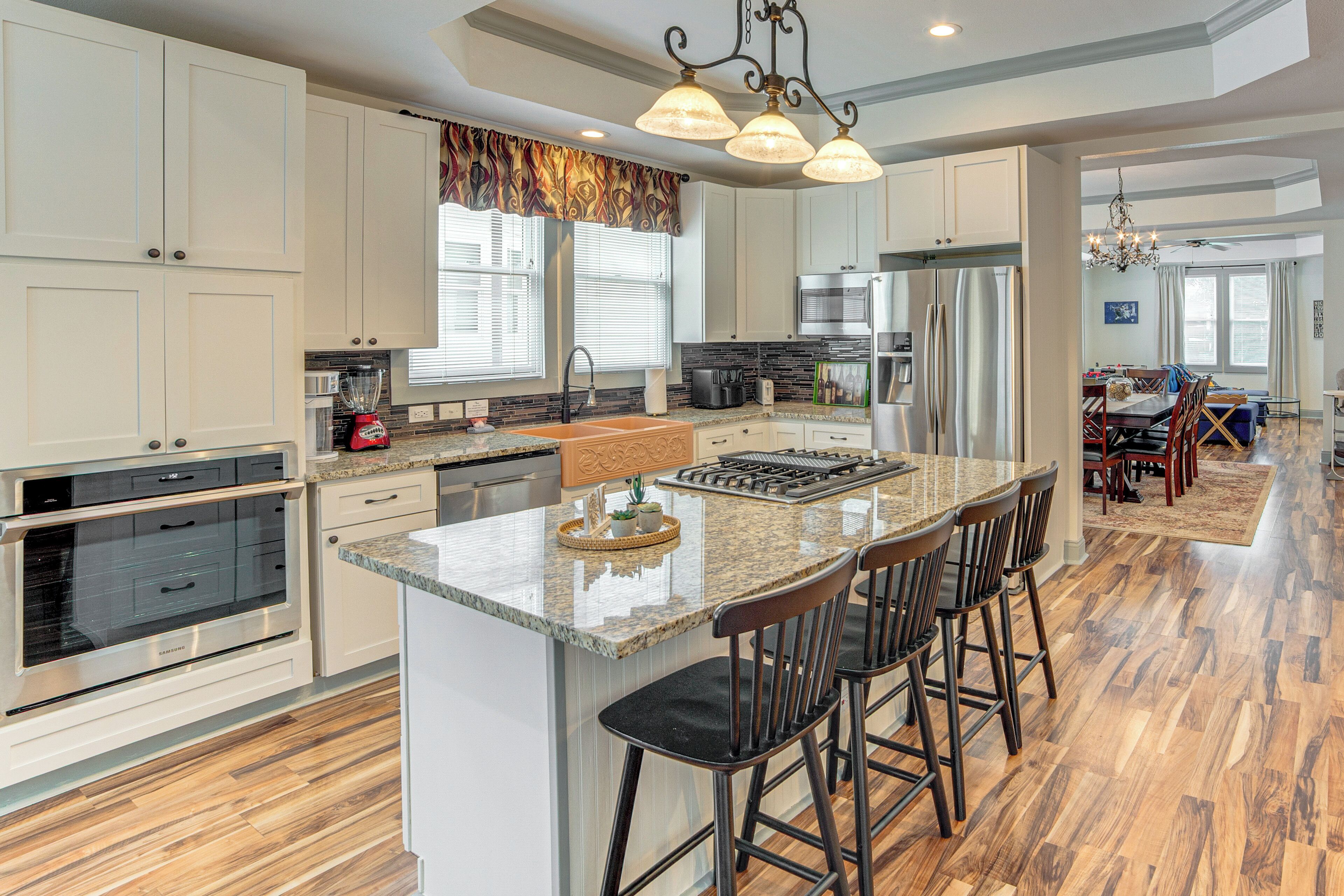 A spacious kitchen with a large island, stainless steel appliances, and a dining area with a chandelier.