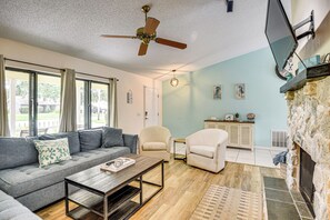 A living room with a sofa, armchairs, a coffee table, a fireplace, and a television mounted on the wall. - 7 Mi to Beach! Poolside Oasis in Port Orange (Port Orange)