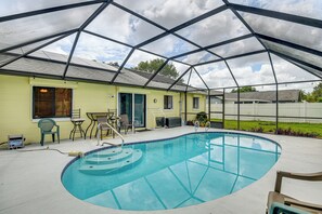 A covered outdoor swimming pool with a glass ceiling, a yellow building with a door and windows, and a fenced yard. - 7 Mi to Beach! Poolside Oasis in Port Orange (Port Orange)