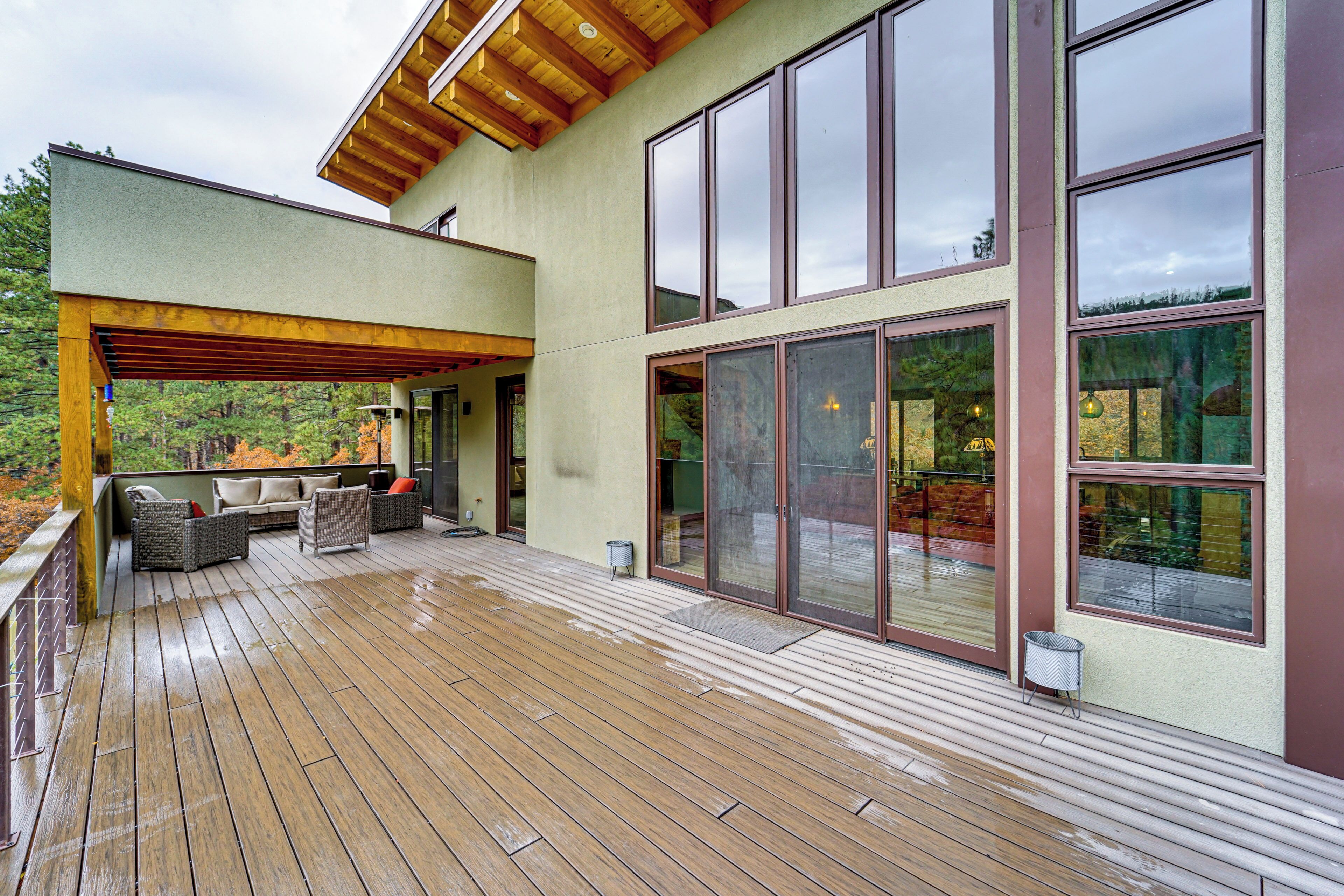 A spacious deck with outdoor seating, large windows, and a wooden ceiling.