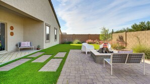 Un jardin avec une terrasse dallée, un banc blanc, un foyer extérieur et un petit espace aménagé en jardin.